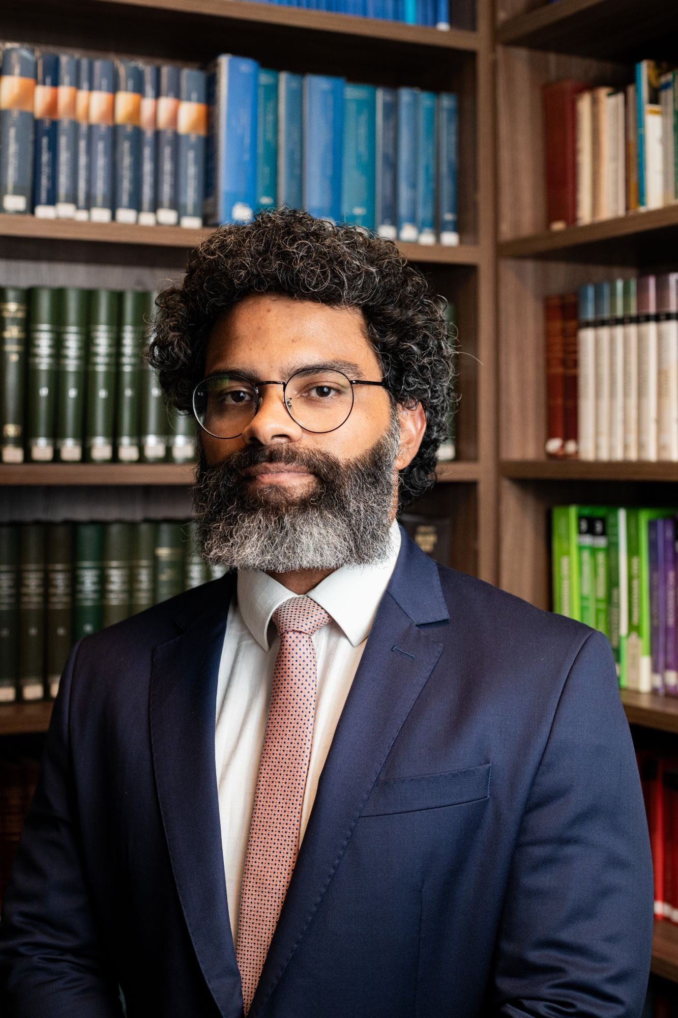 Vinícius Assumpção diante de uma estante de livros